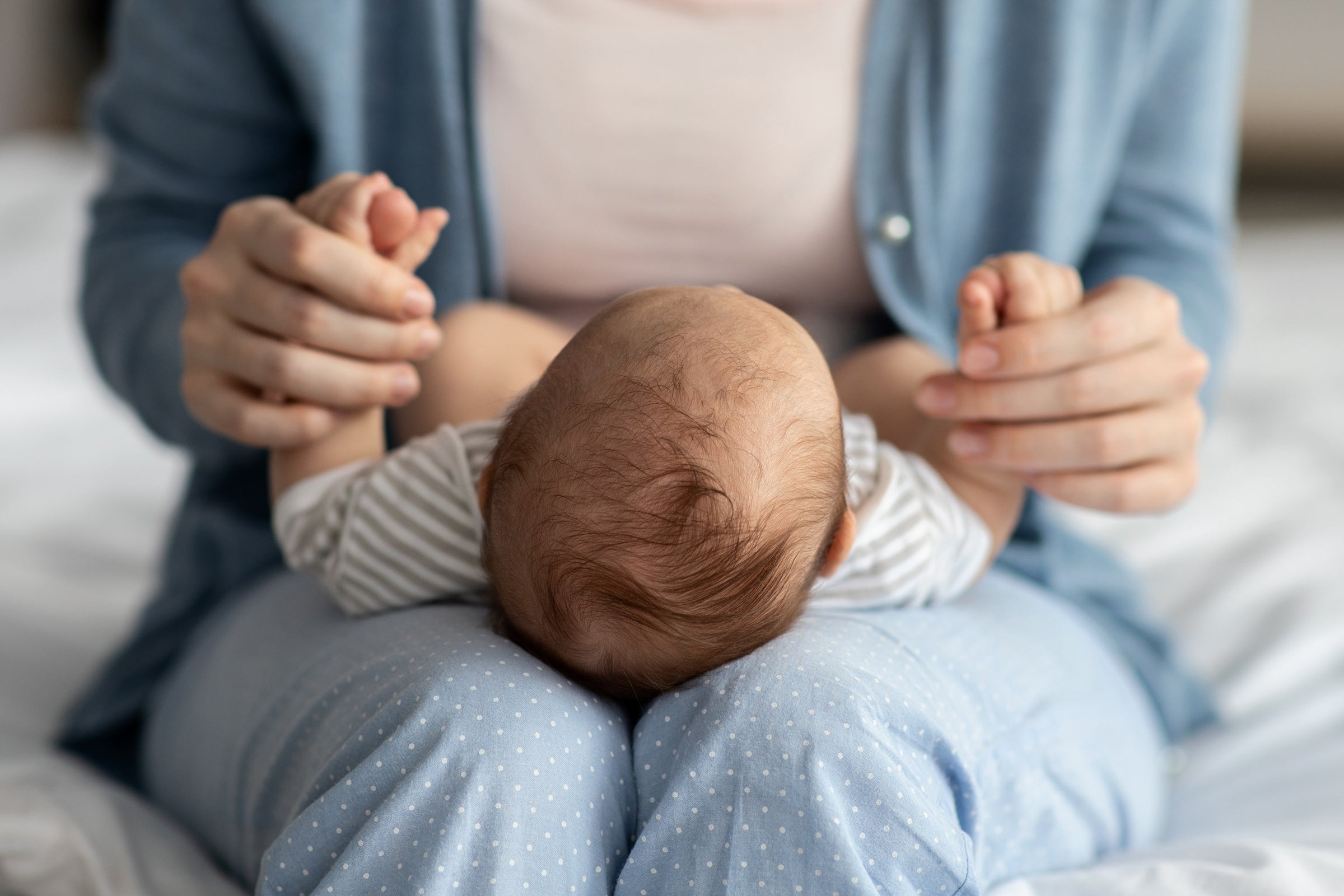 A small baby lies in a woman's lap